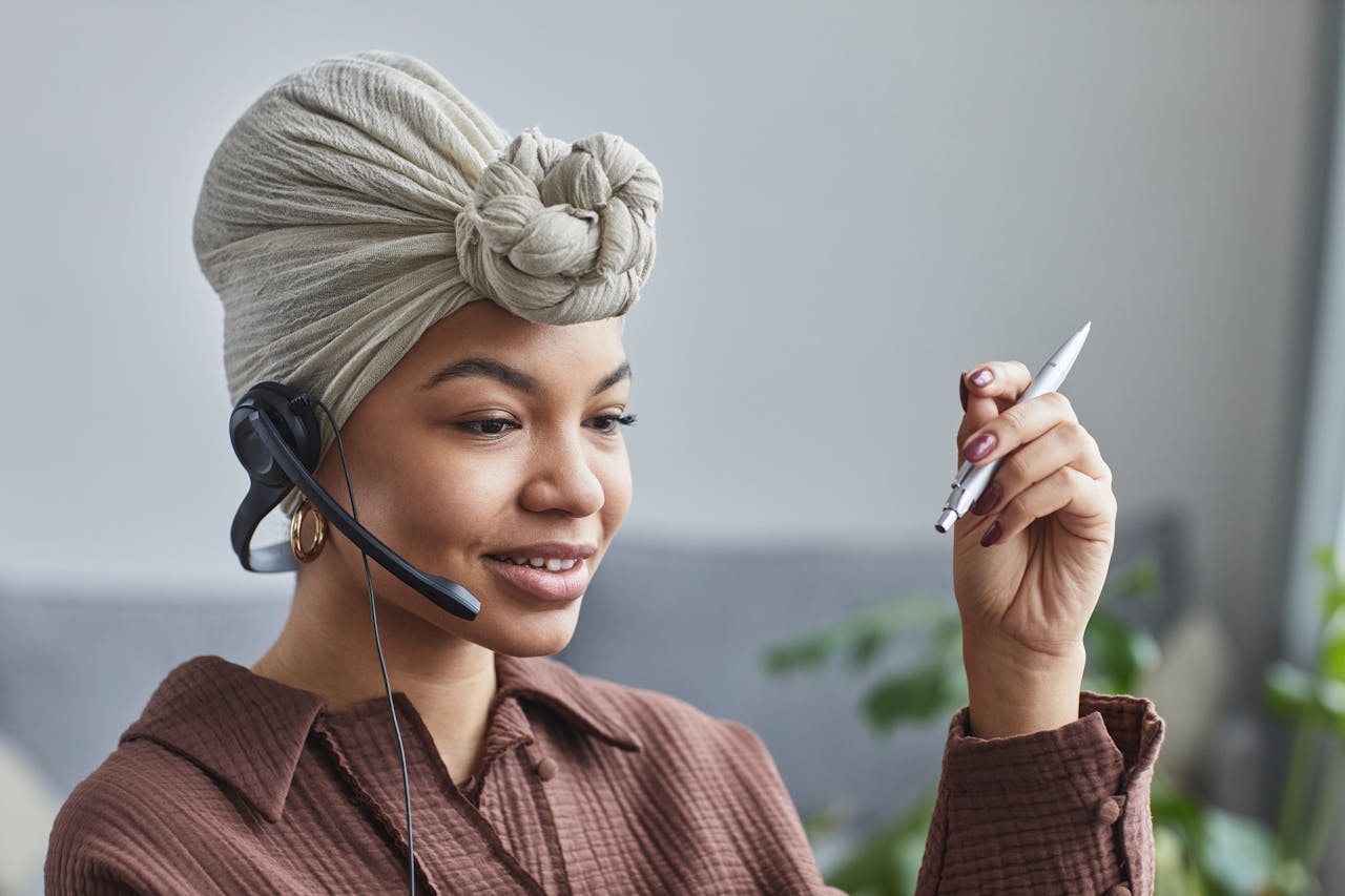Home Smiling woman wearing a headset while working at a call center, looking engaged and professional.